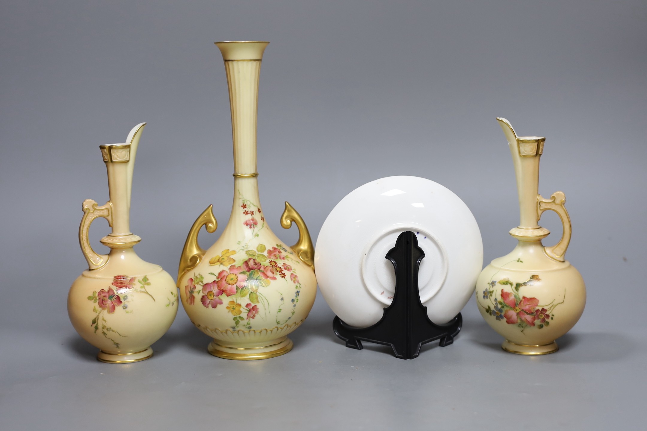 A pair of Royal Worcester blush ivory ewers, a similar vase and a beaded saucer decorated by E. Townsend, saucer 13.5cms diameter